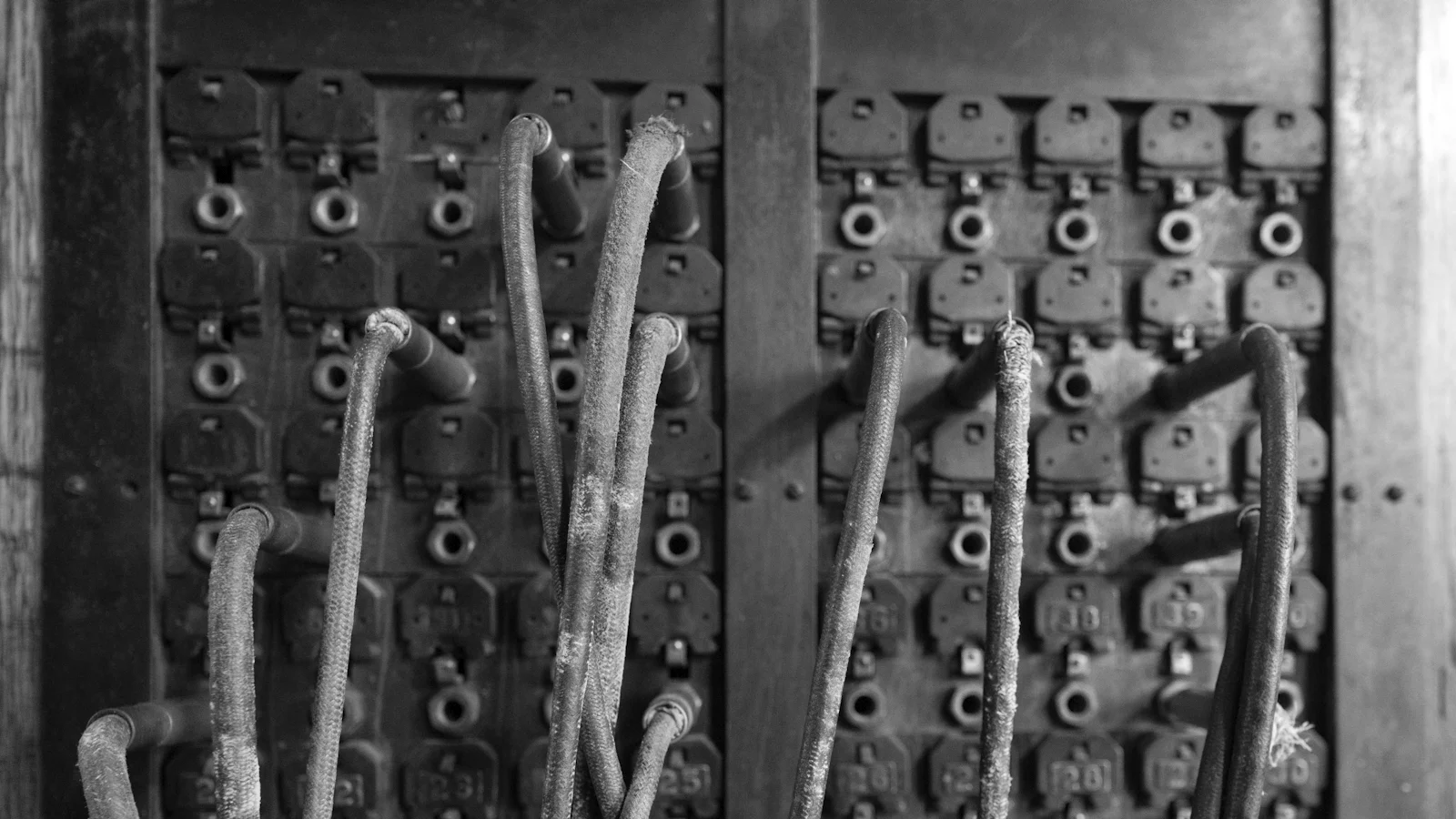 Patch cords plugged into the numbered jack field of an antique telephone switchboard